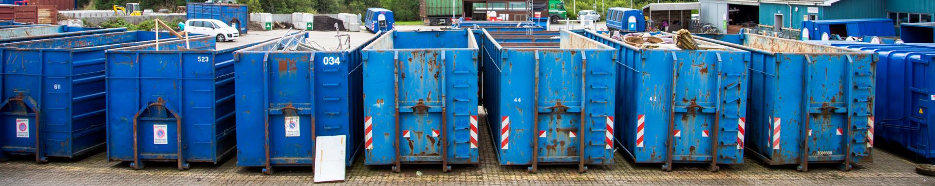 Blå containere fra en genbrugsplads står på række
