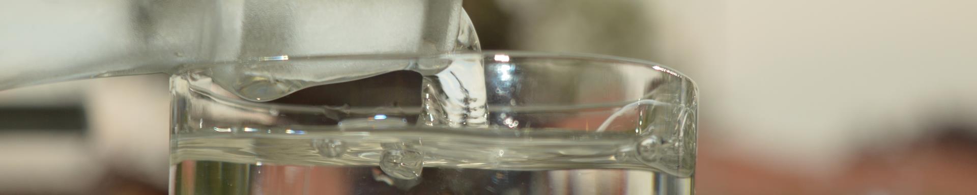 Et nærbillede af koldt postevand der bliver hældt op fra en flaske til et glas