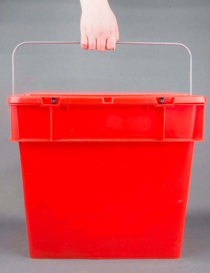 Her ser man en rød kasse med et metalhåndtag og en hånd der holder i håndtaget. 