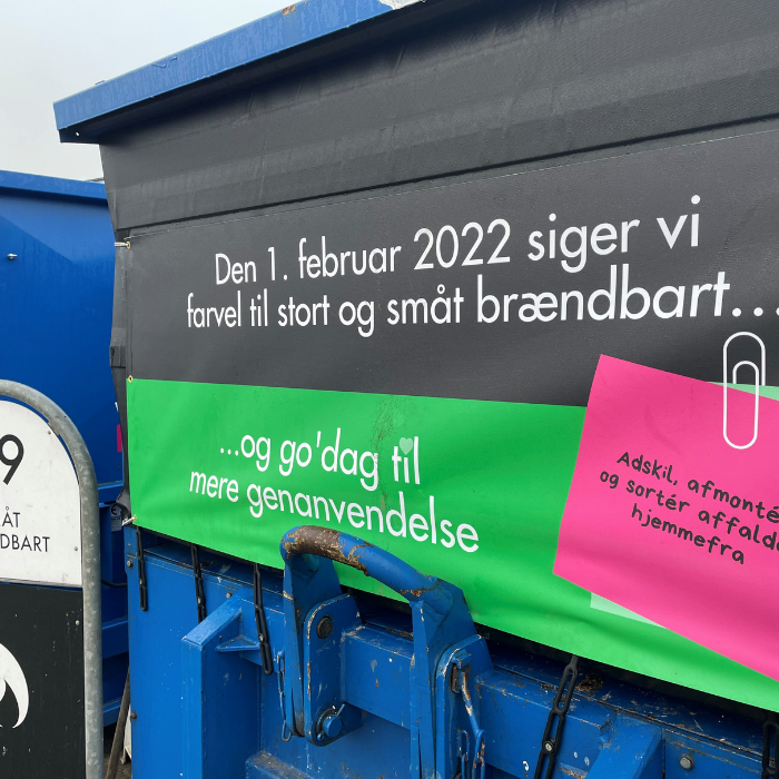 En banner der hænger på en blå affaldscontainer