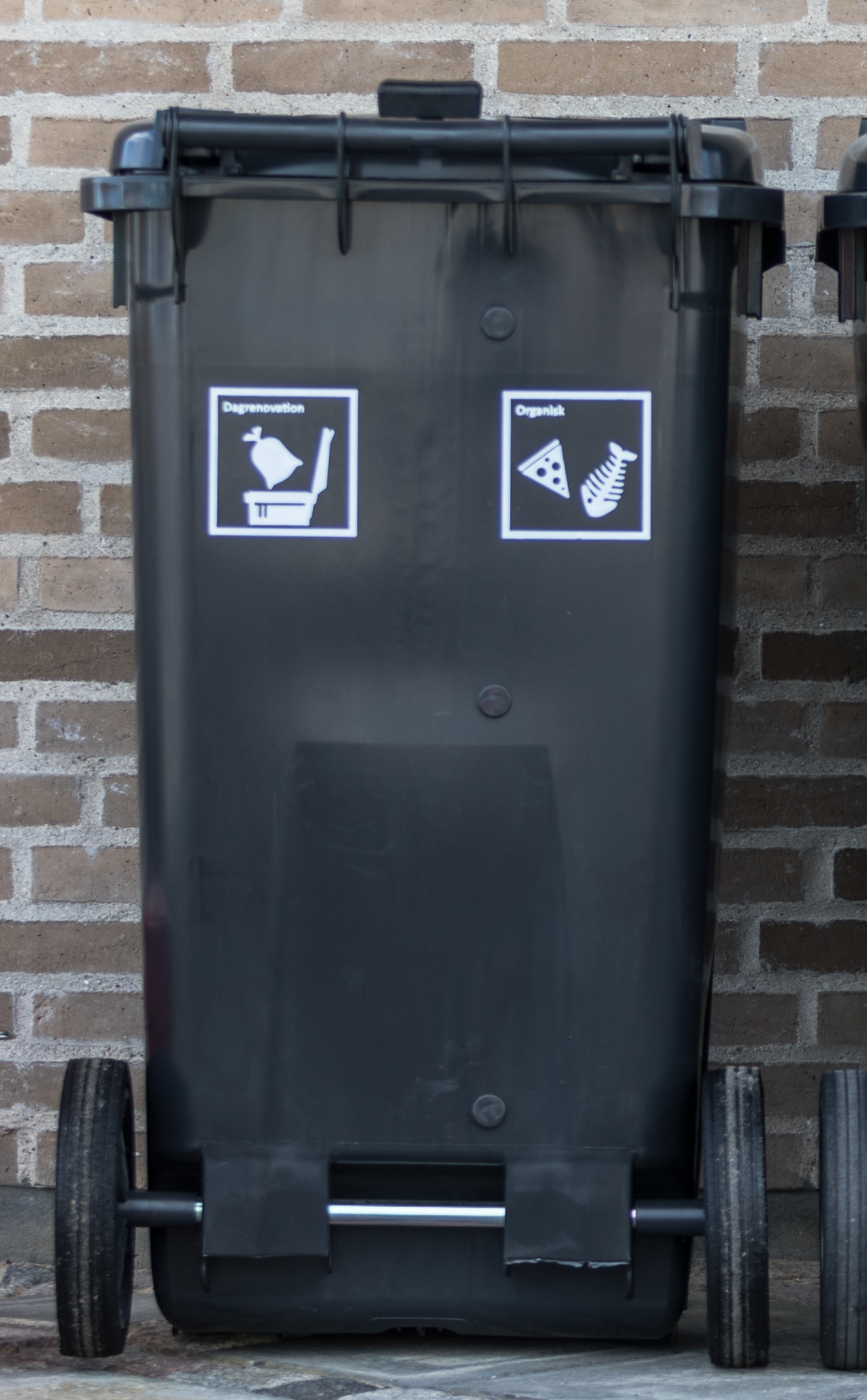 En sort affaldscontainer med to hvide piktogrammer på fronten