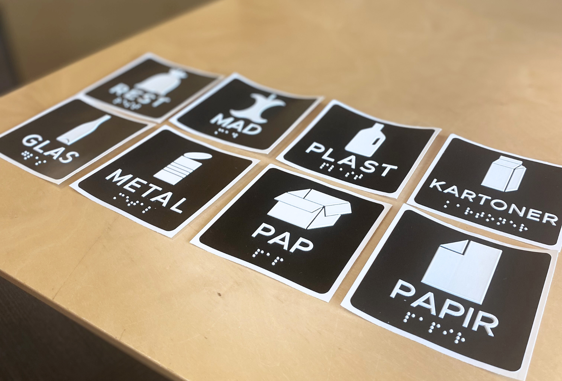 Her ser man de otte varianter af taktile skilte som Vesthimmerlands Forsyning tilbyder. Det drejer sig om henholdsvis pap, papir, glas, metal, plast, mad- og drikkekartoner, madaffald og restaffald. 